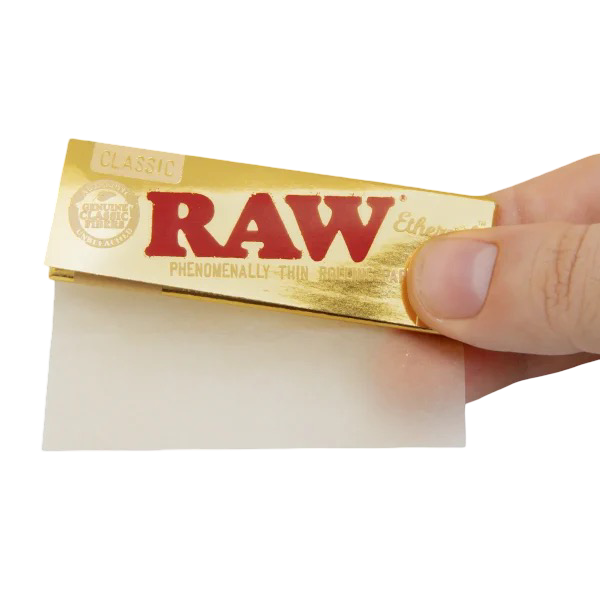 Papel RAW Ethereal Classic dorado sostenido con la mano, muestra del grosor ultrafino y acabado premium.